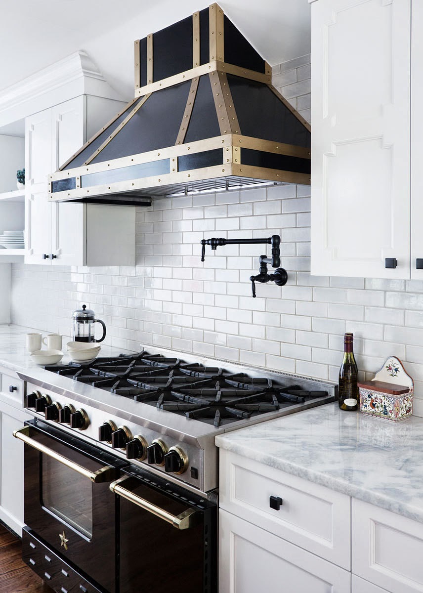 A black and white kitchen with a gold hood, transformed by a new kitchen range hood.