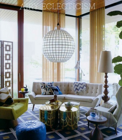A living room with colorful furniture and a large chandelier, designed by the King of Happy Chic, Jonathan Adler.