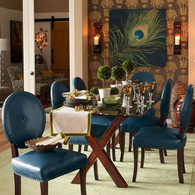 A dining room with inspiring blue chairs and a beautiful peacock painting.