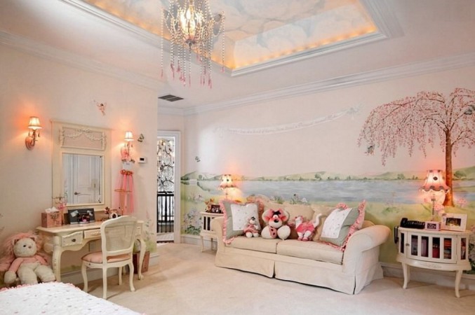 A pink and white kids room with a chandelier.