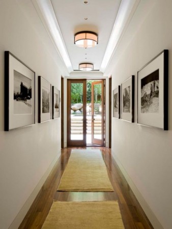 A hallway with framed pictures and a rug.