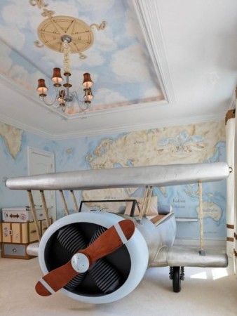 A kids room with an airplane bed and a map on the wall.