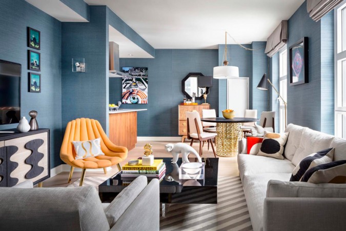 A living room with blue walls and white furniture, designed by Jonathan Adler.