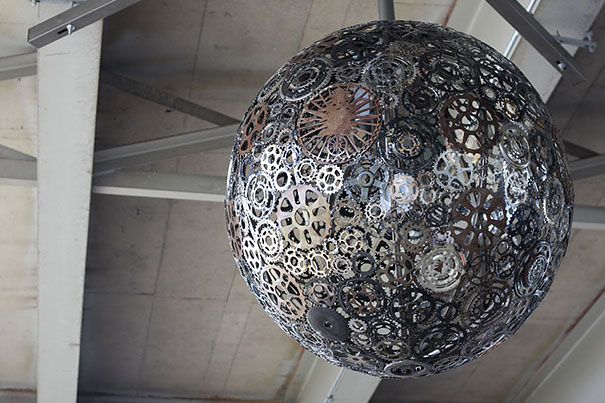 An intriguing repurposed light fixture - a large metal ball hanging from a ceiling.