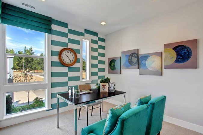 A stylish home office with striped walls and a clock.