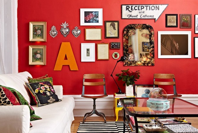 A living room with red walls and unique gallery wall.