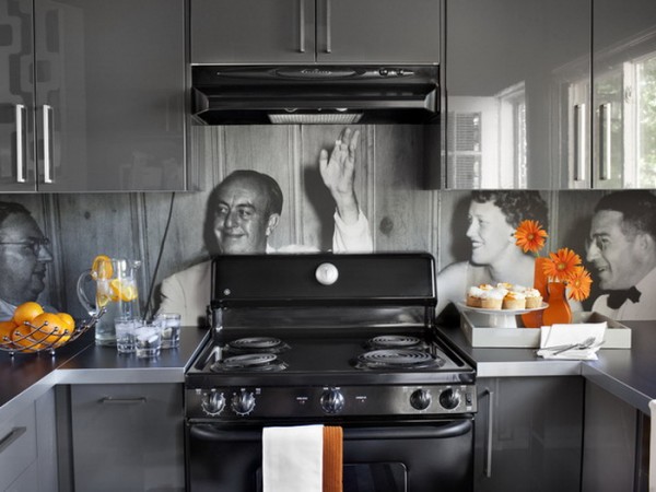 A kitchen with a black stove and orange and black pictures on the wall showcasing beautiful backsplash ideas.
