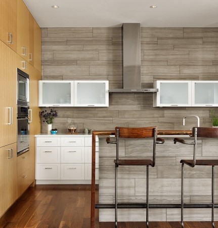 A modern kitchen with beautiful wood floors and trendy bar stools.