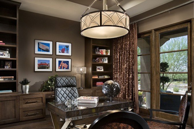 A stylish home office with brown furniture and a chandelier.