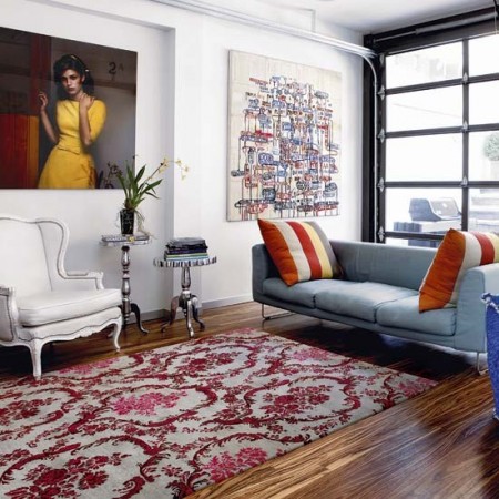 A living room with a beautiful blue couch and a colorful rug in a city apartment.