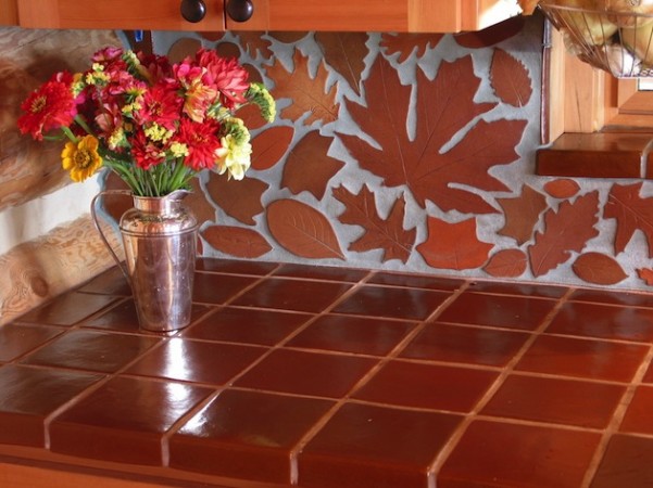 A kitchen with a brown tile countertop and flowers in a vase, showcasing beautiful backsplash ideas.