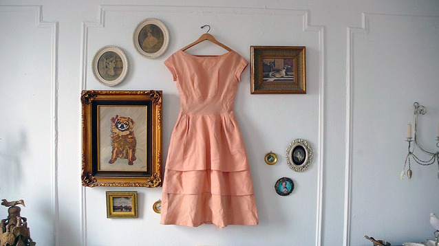 A pink dress hangs on a unique gallery wall.