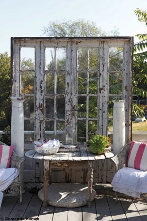 Repurposed window showcases wicker furniture on a charming patio.