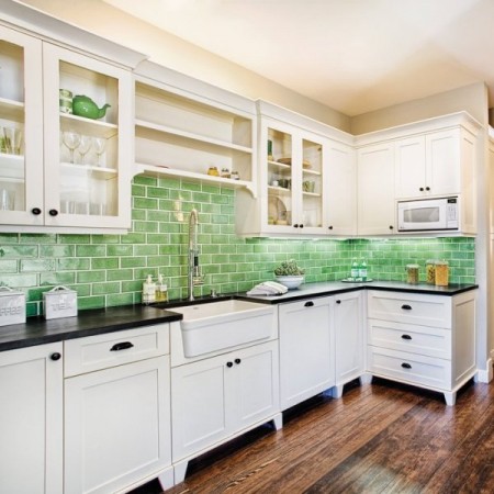 A white kitchen with beautiful green tile backsplash and white cabinets.