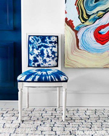 A vibrant chair in front of a blue and white painting.