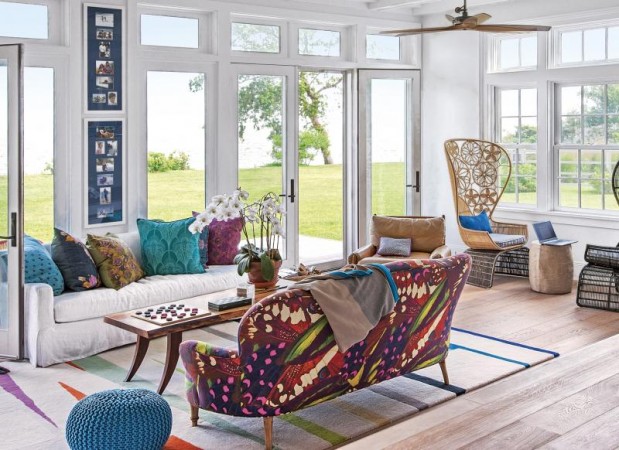 A living room with vibrant upholstery and large windows.