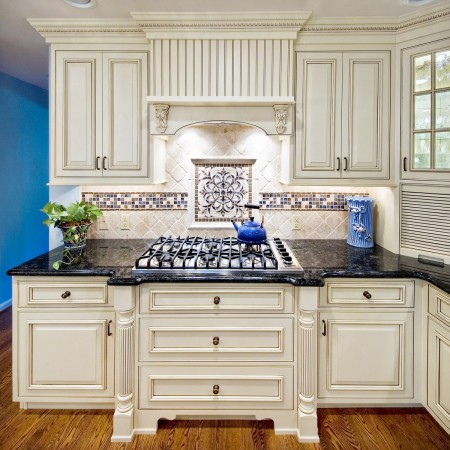 A kitchen with white cabinets and a black stove top featuring beautiful backsplash ideas.