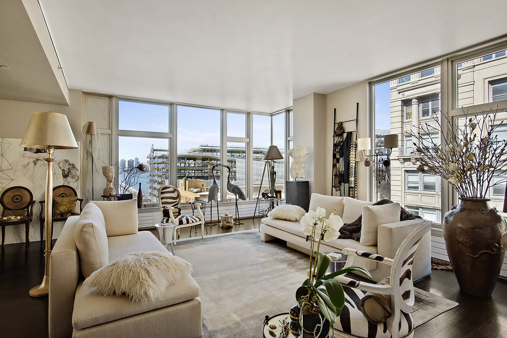 A large living room with large windows and large furniture in a beautiful city apartment.