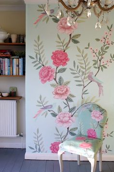 A room with a chair and a floral wall.