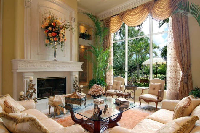 A bold living room with a beautiful fireplace and large windows in Palm Beach style.
