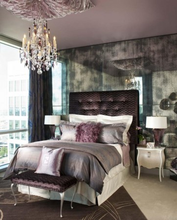 A purple bedroom with a chandelier and a bed exuding shimmer and luster.