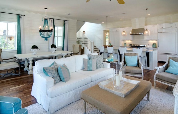 A chic beach-inspired living room with a white and blue color scheme and a ceiling fan.