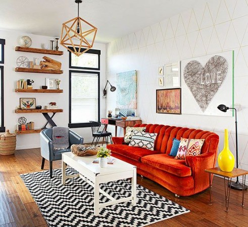 A living room with a funky orange couch and a cool black and white chevron rug.
