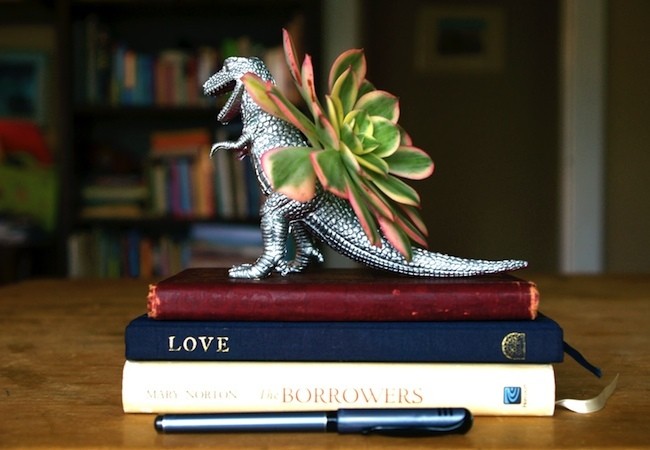 A t-rex statue sits on top of a stack of books, upcycling.