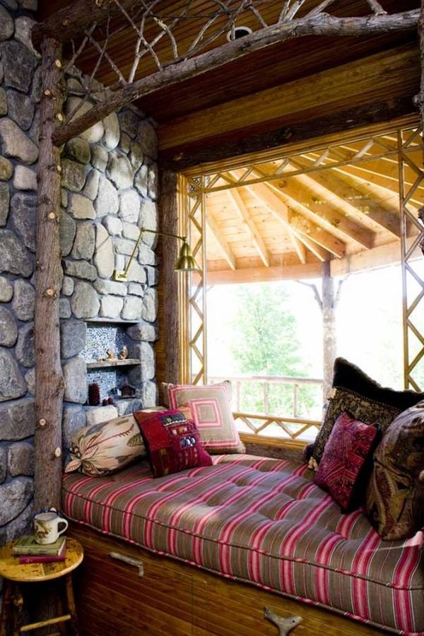 A cozy bed in a room with a fireplace and charming stone wall, featuring inviting nooks.