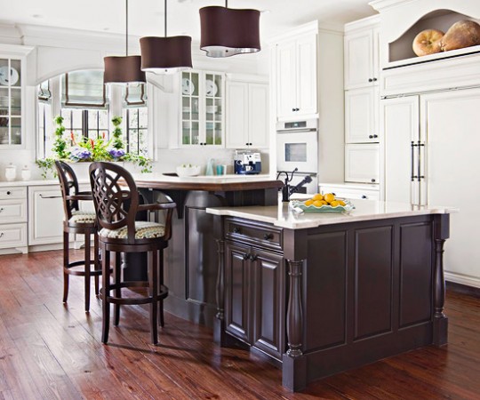 A kitchen with a center island and mixed cabinet finishes.
