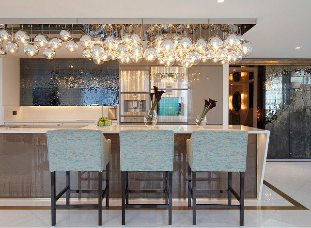 A modern kitchen with a chandelier and bar stools, adding shimmer and luster to your home.