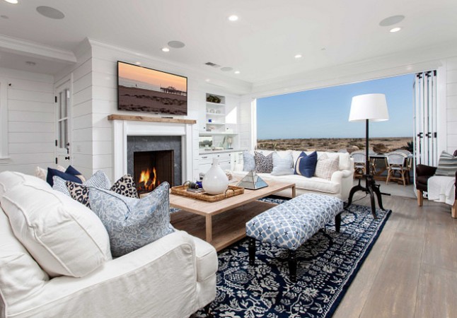 A living room with white furniture and a fireplace, inspired by a chic beach look.