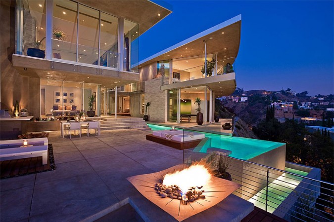 A luxurious house with a fire pit at night.