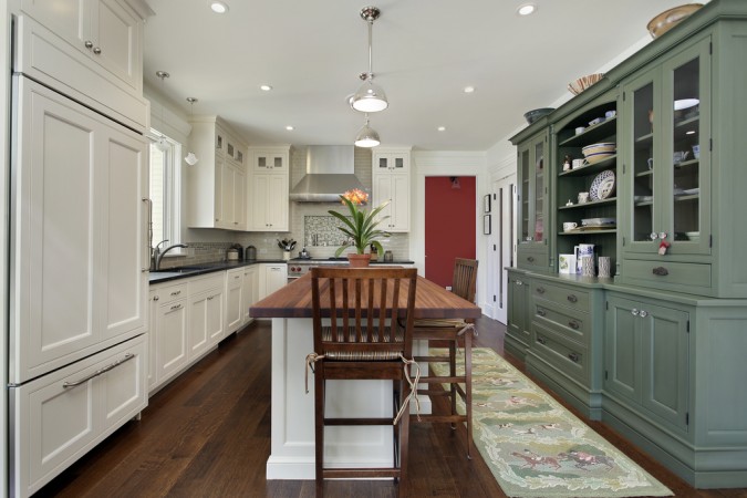 Beautiful green stained cabinet gives a color boost to white kitchen cabinetry 