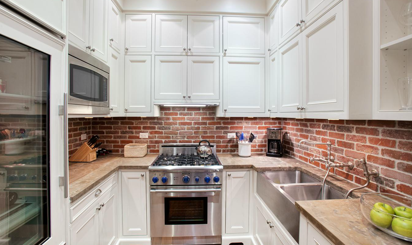 A small kitchen with a stunning back-splash and stainless steel appliances.