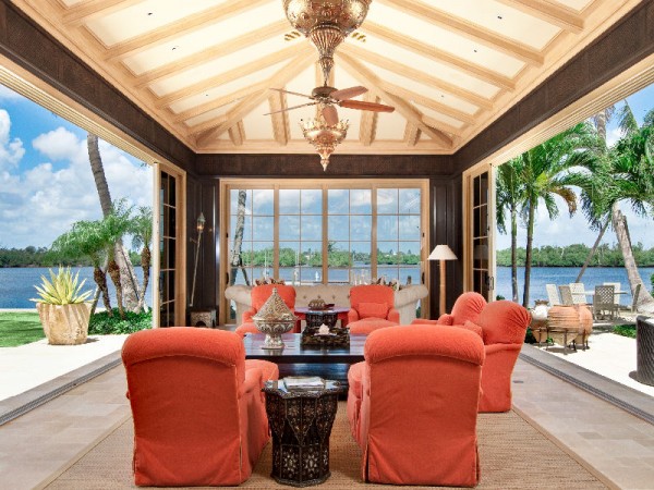 A living room with bold orange chairs and a ceiling fan, exuding Palm Beach style.