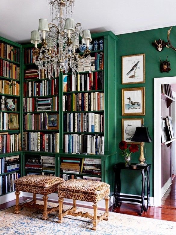 A glamorous living room with emerald green walls and bookshelves.