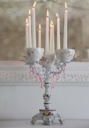 A repurposed tea set transformed into a teacup candle holder with candles on it.