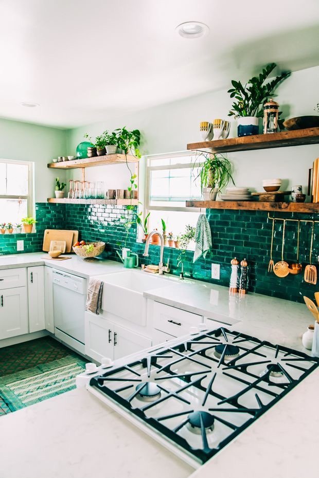 A glamorous kitchen with emerald green tiled walls and a stove.