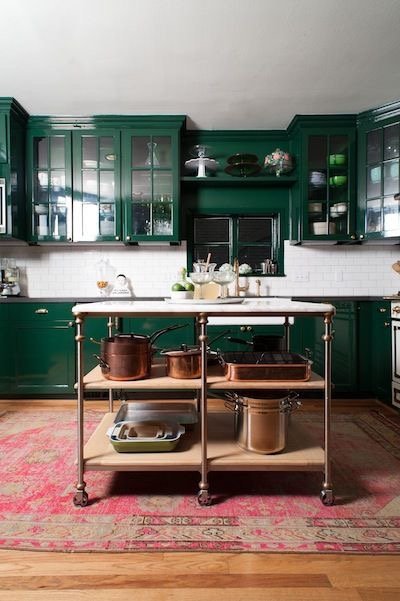 A glamorous kitchen with emerald green cabinets and an island.