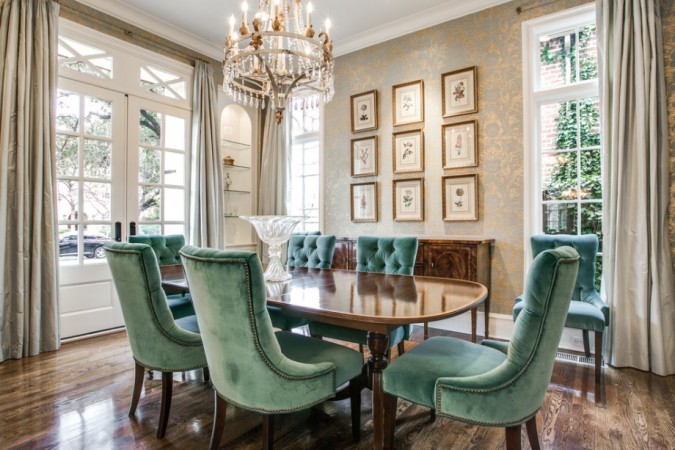 A dining room with green chairs and a chandelier is making a comeback.