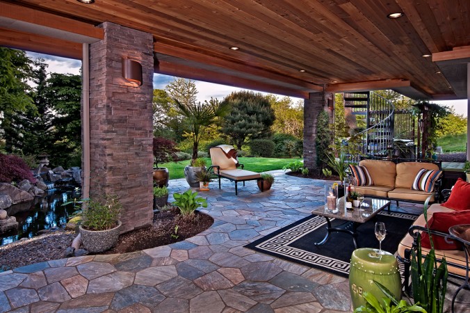 A luxury outdoor living area with a fireplace and a pond.