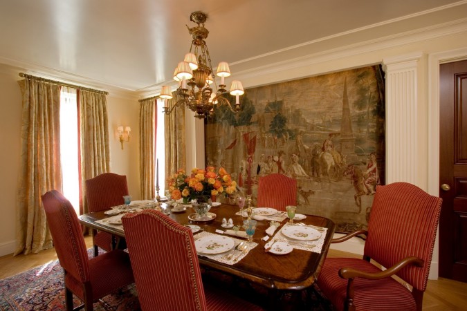 A formal dining room with red chairs and a tapestry is making a comeback.