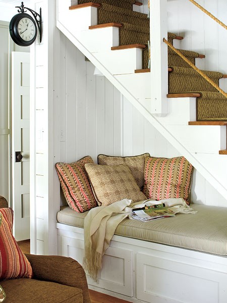 A room with cozy nooks featuring a bed under the stairs and a comfortable couch.