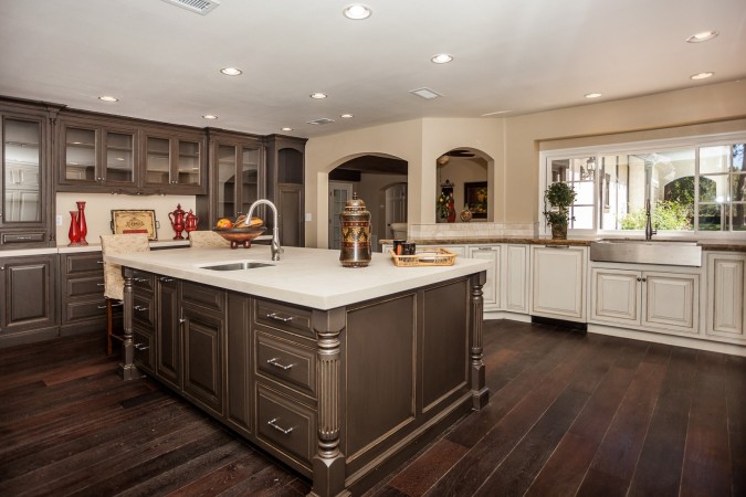 A kitchen with a center island and trendy mixed cabinet finishes.