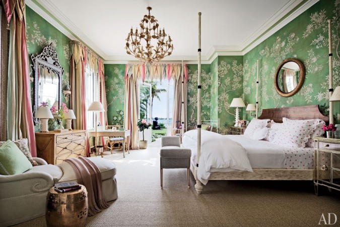 A beautiful bedroom with bold floral wallpaper and a chandelier in Palm Beach style.