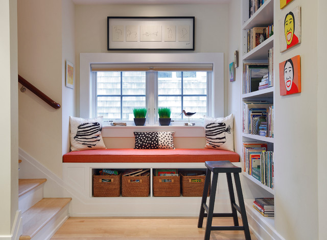 A cozy nook with bookshelves and a window seat in a hallway.