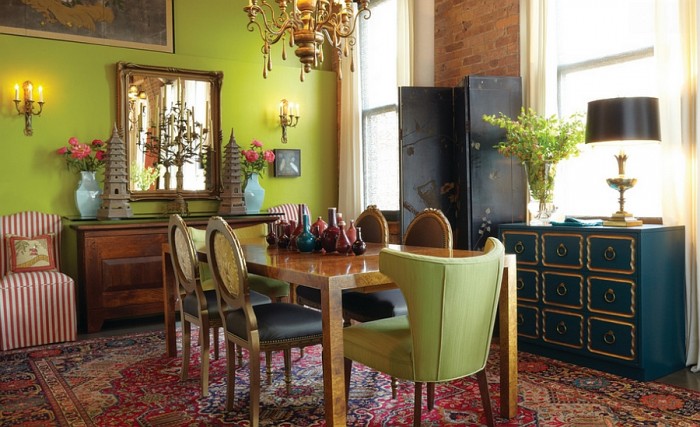 A dining room with green walls and a green rug, emphasizing the comeback of formal dining.