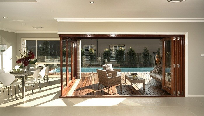 A luxurious indoor-outdoor living room with sliding glass doors and a pool.