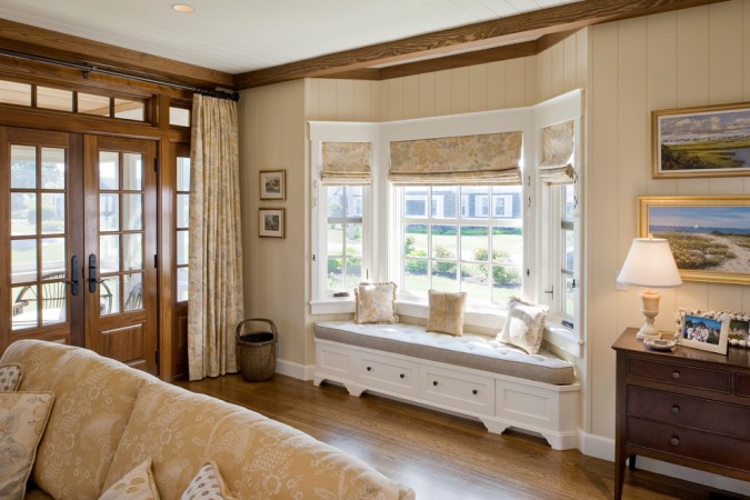 A cozy living room with large windows and a window seat.